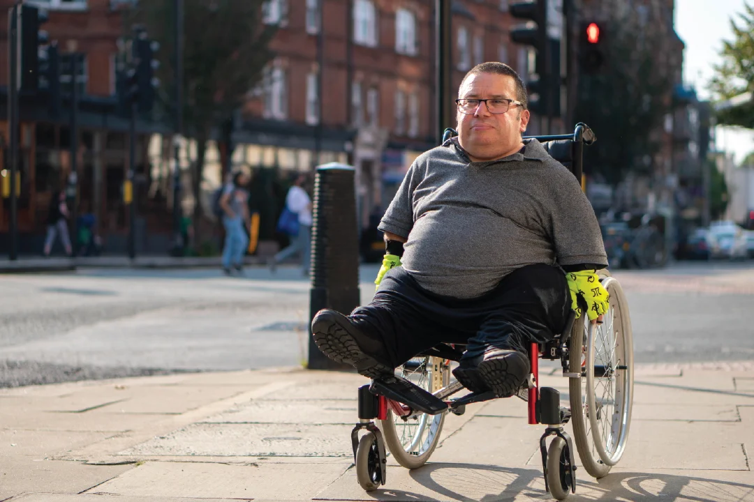 man in wheelchair navigating sidewalk